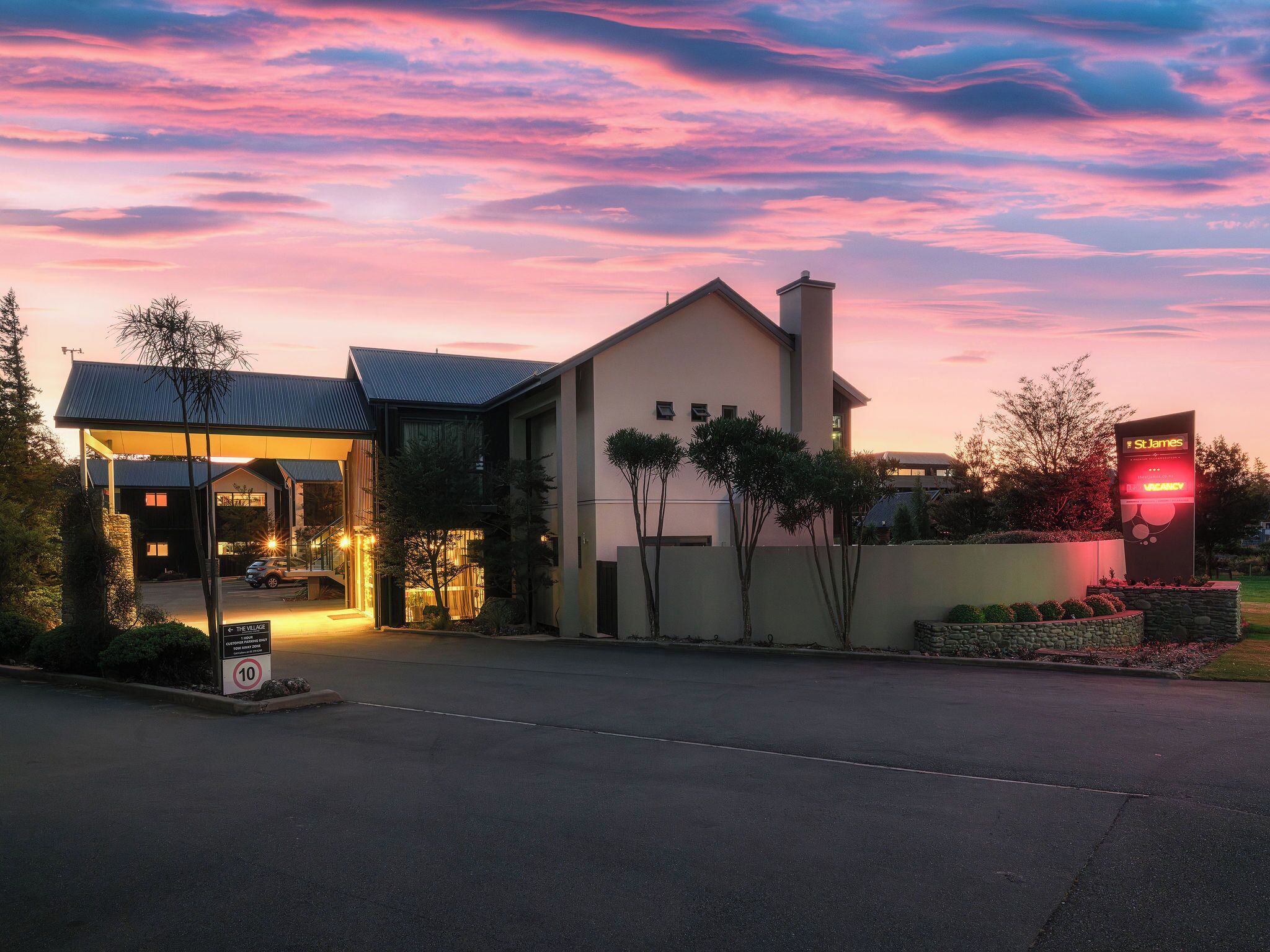 A modern hotel with a covered entrance, a sign indicating vacancy, and a well-maintained driveway.