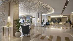 A modern lobby with a geometric ceiling design, a reception desk, seating area, and a cafe. - Two Seasons Hotel & Apartments (Dubai)