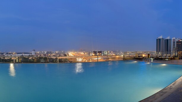 A swimming pool with city views, lounge chairs, and a modern building facade. - Two Seasons Hotel & Apartments (Dubai)