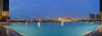 A swimming pool with city views, lounge chairs, and a modern building facade.