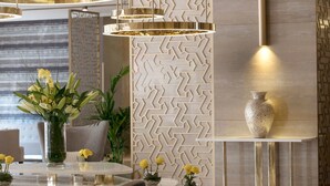 A modern interior with a geometric patterned wall, a round dining table with chairs, and a vase with yellow flowers. - Two Seasons Hotel & Apartments (Dubai)