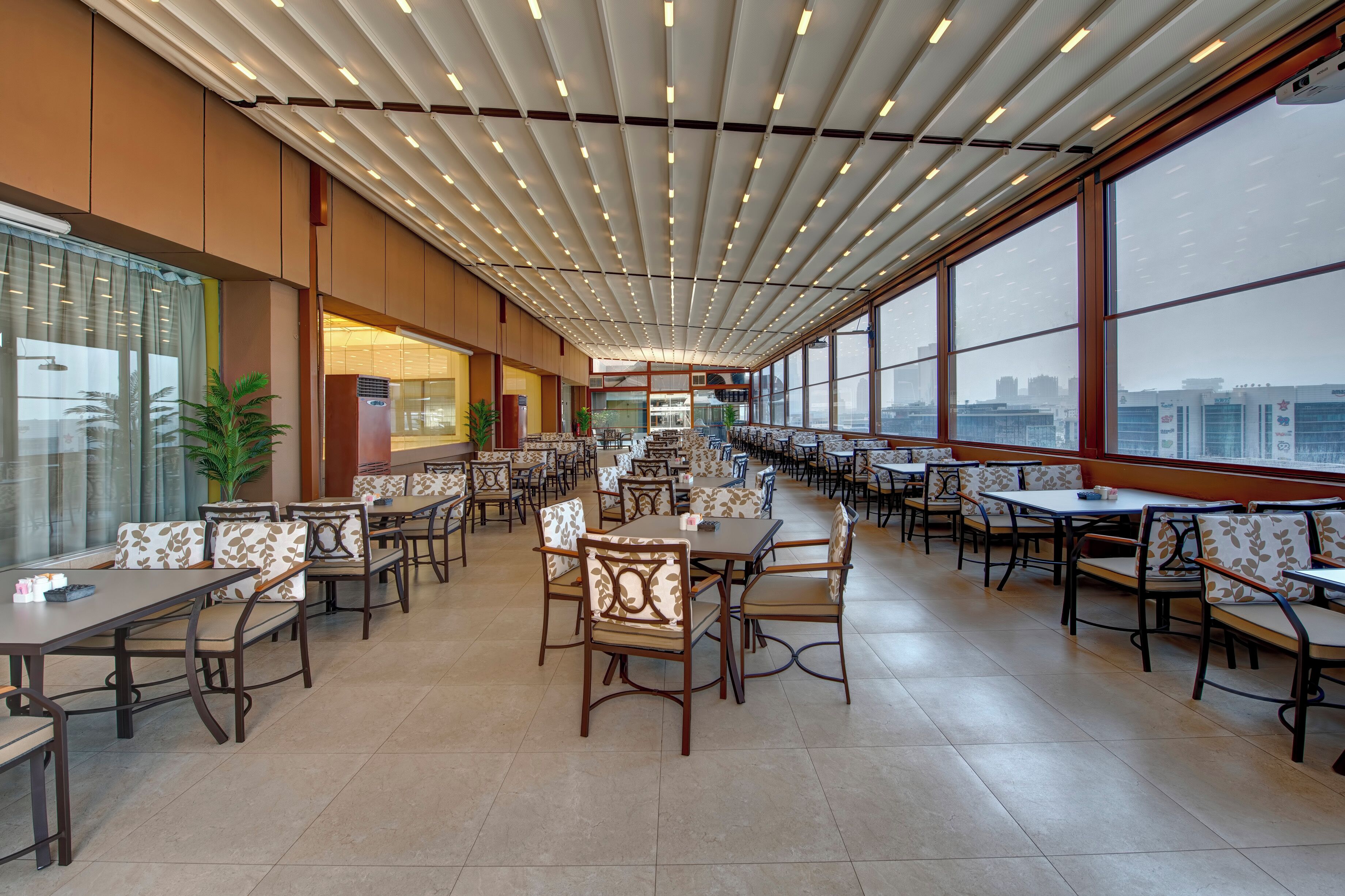 A spacious indoor dining area with high ceilings, large windows, and modern furniture.