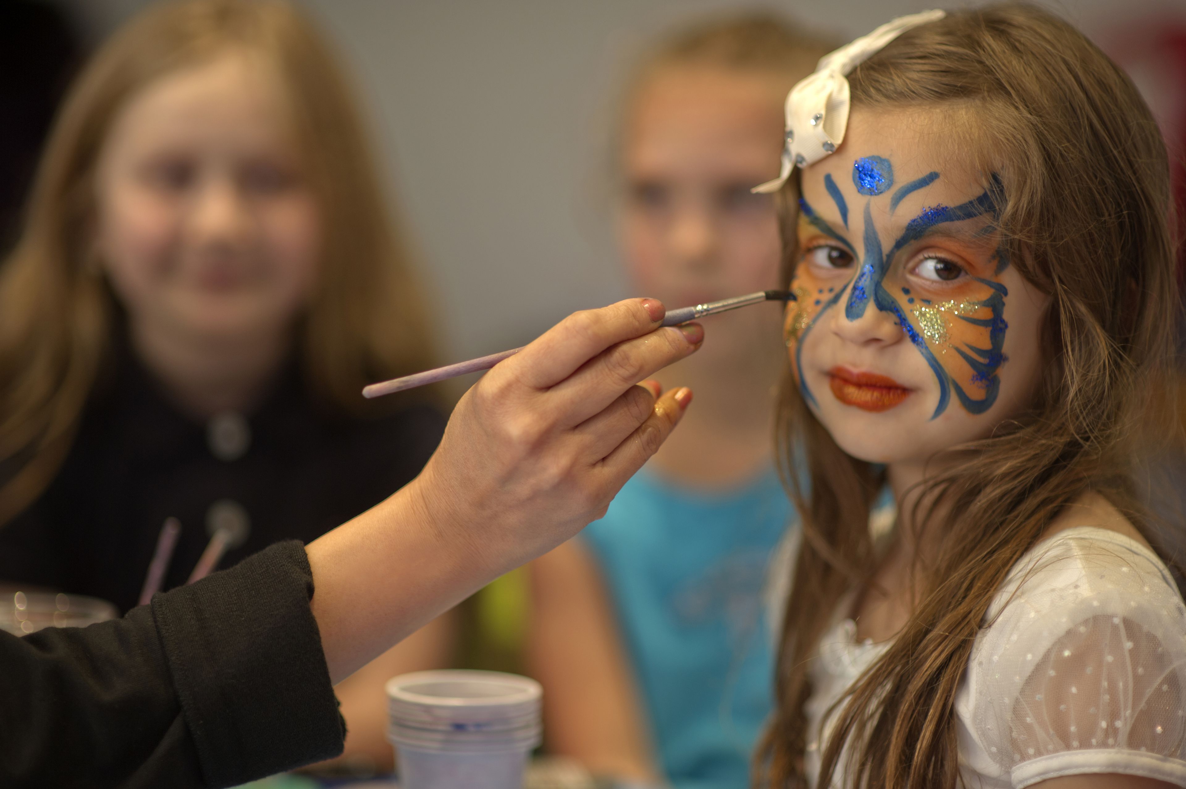A person painting another person's face with blue and gold colors.