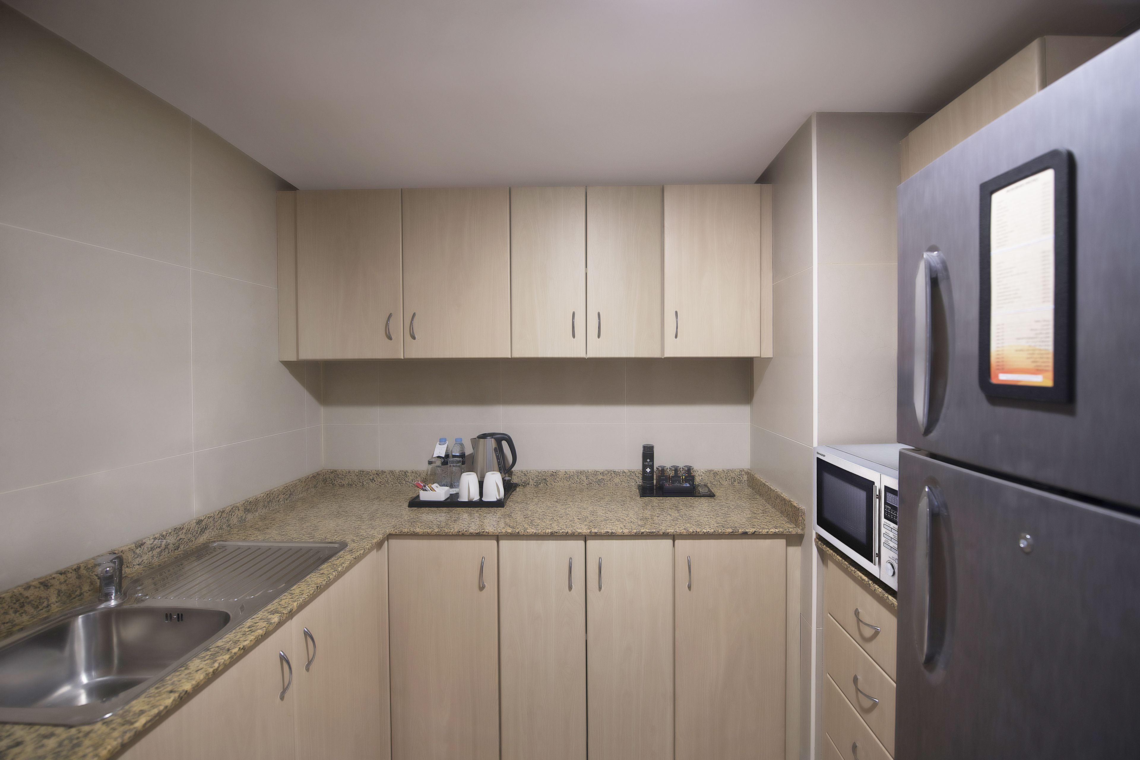 Una cocina con un lavamanos de acero inoxidable, un microondas y un refrigerador.