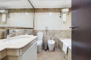 A modern bathroom with a large sink, toilet, bidet, and bathtub.