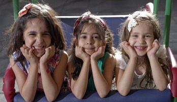 Three children sitting on a playground structure.