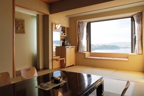 A hotel room with a large window, a dining table, a sofa, and a small kitchen area. - THE FOREST AKAN TSURUGA RESORT (Kushiro)