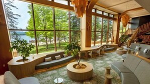 Amplia sala de estar con ventanas grandes, una mesa redonda de madera para café y una zona de estar integrada.