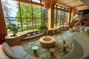 Amplia sala de estar con ventanas grandes, una mesa redonda de madera para café y una zona de estar integrada.