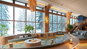 Un interior moderno con ventanas amplias, una zona de estar curvada y una escalera.