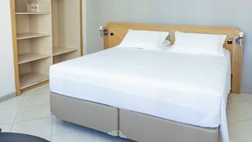 Una habitación de hotel con una cama, un armario y un escritorio.