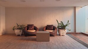 Amplia habitación con dos sillones de mimbre, una mesa de centro tejida y plantas en macetas.