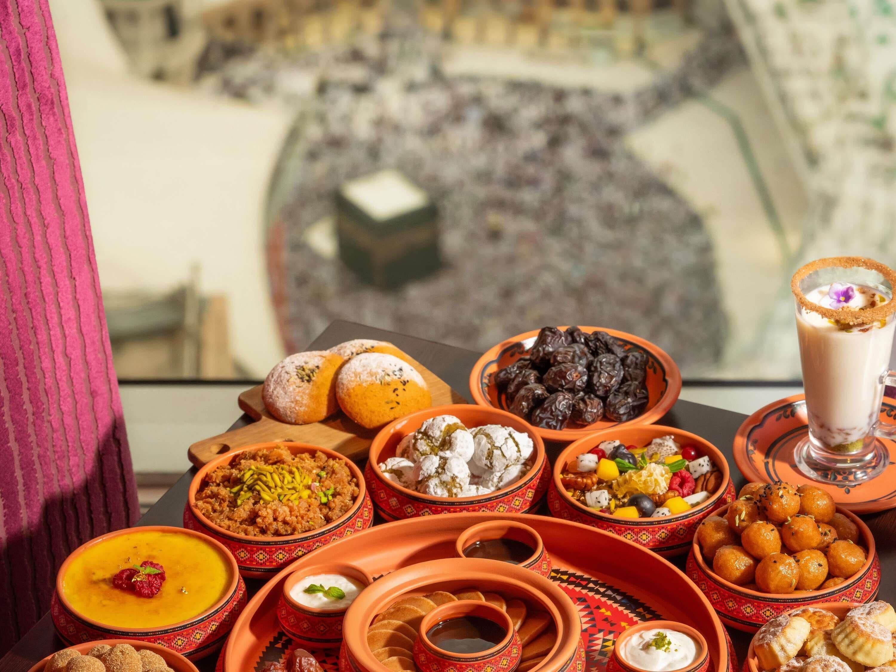 Una mesa con diversos platos tradicionales y vista a una plaza concurrida.