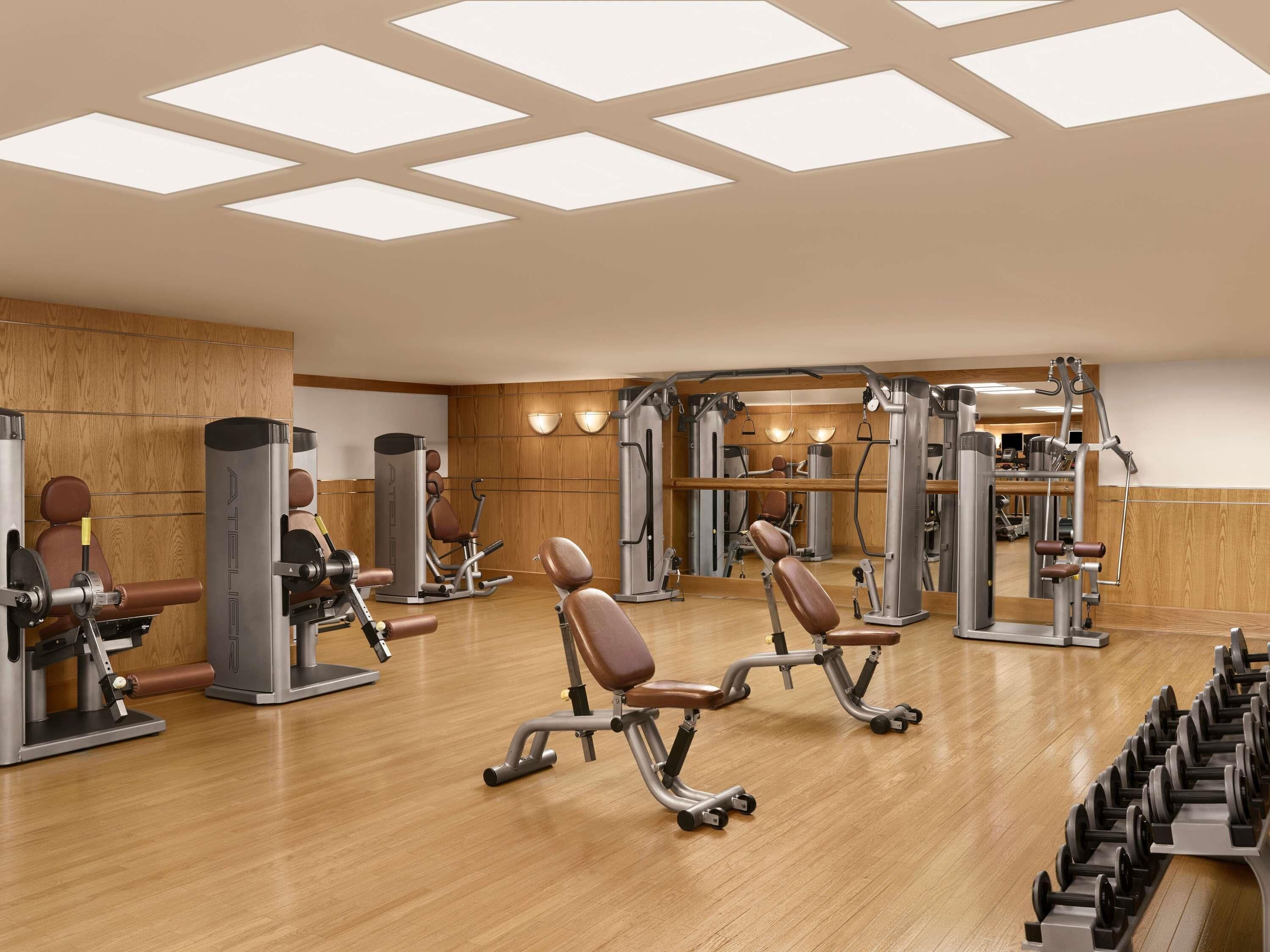 A gym with exercise equipment, wooden flooring, and a large mirror.