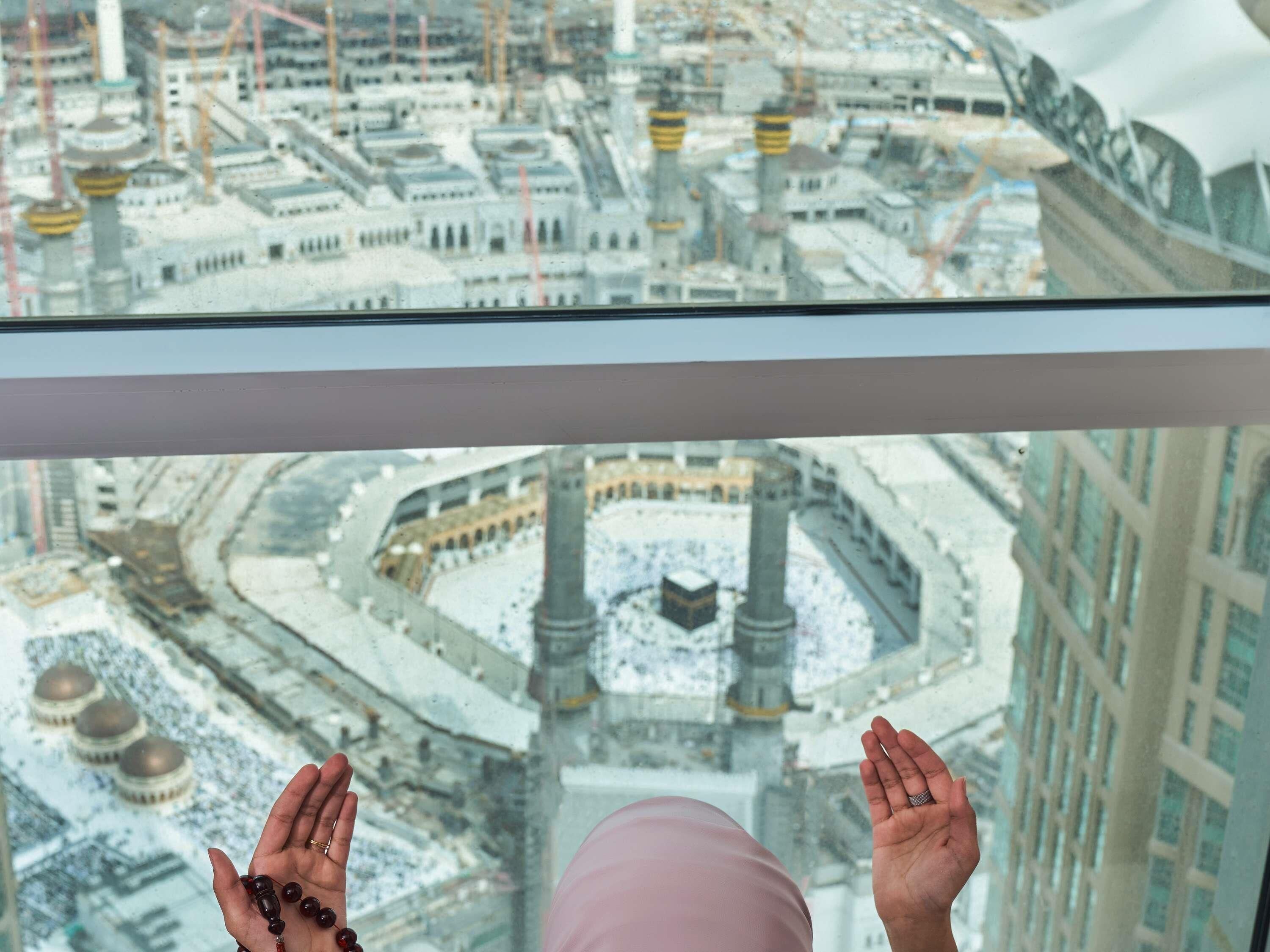 Visão de um horizonte urbano com uma grande mesquita e minaretes, uma pessoa com as mãos levantadas e um edifício com telhado curvo.