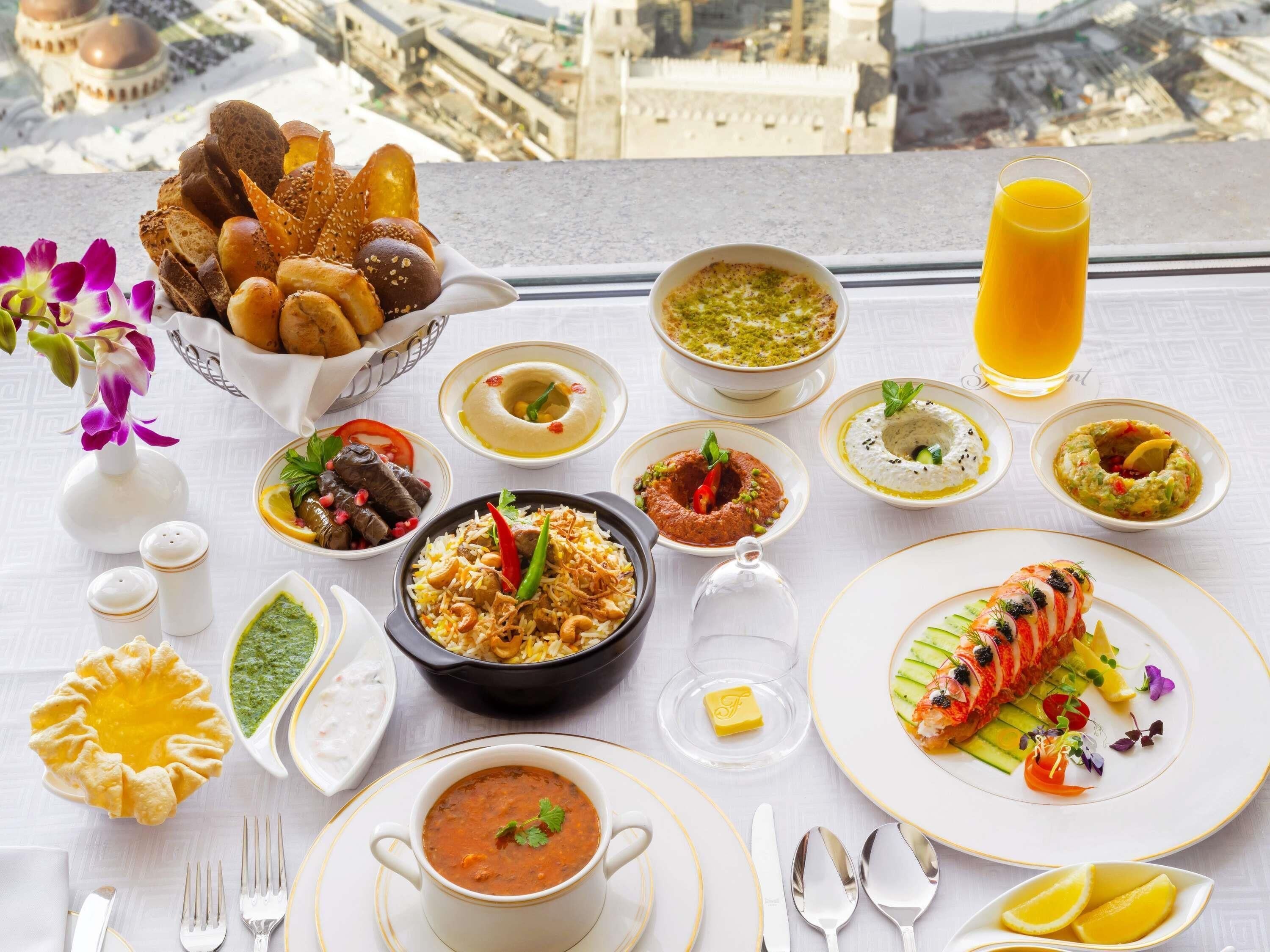A table with various dishes, a glass of orange juice, and a view of a cityscape.
