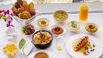 A table with various dishes, a glass of orange juice, and a view of a cityscape.
