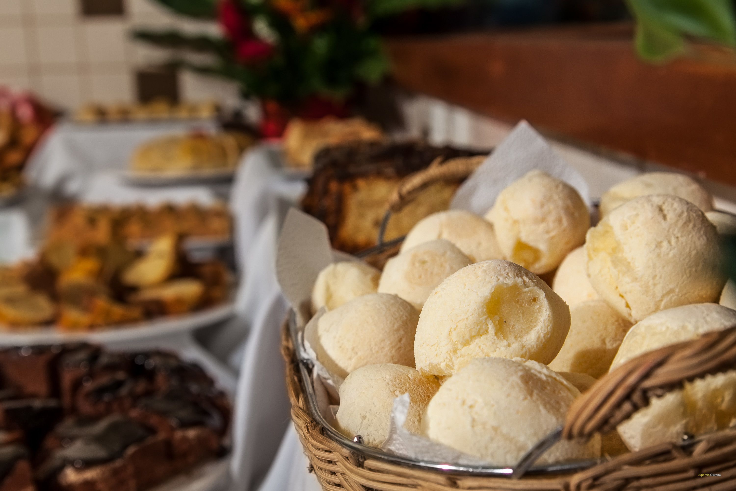 Una mesa de buffet con diversos alimentos, incluyendo una cesta de bollos redondos y blancos.