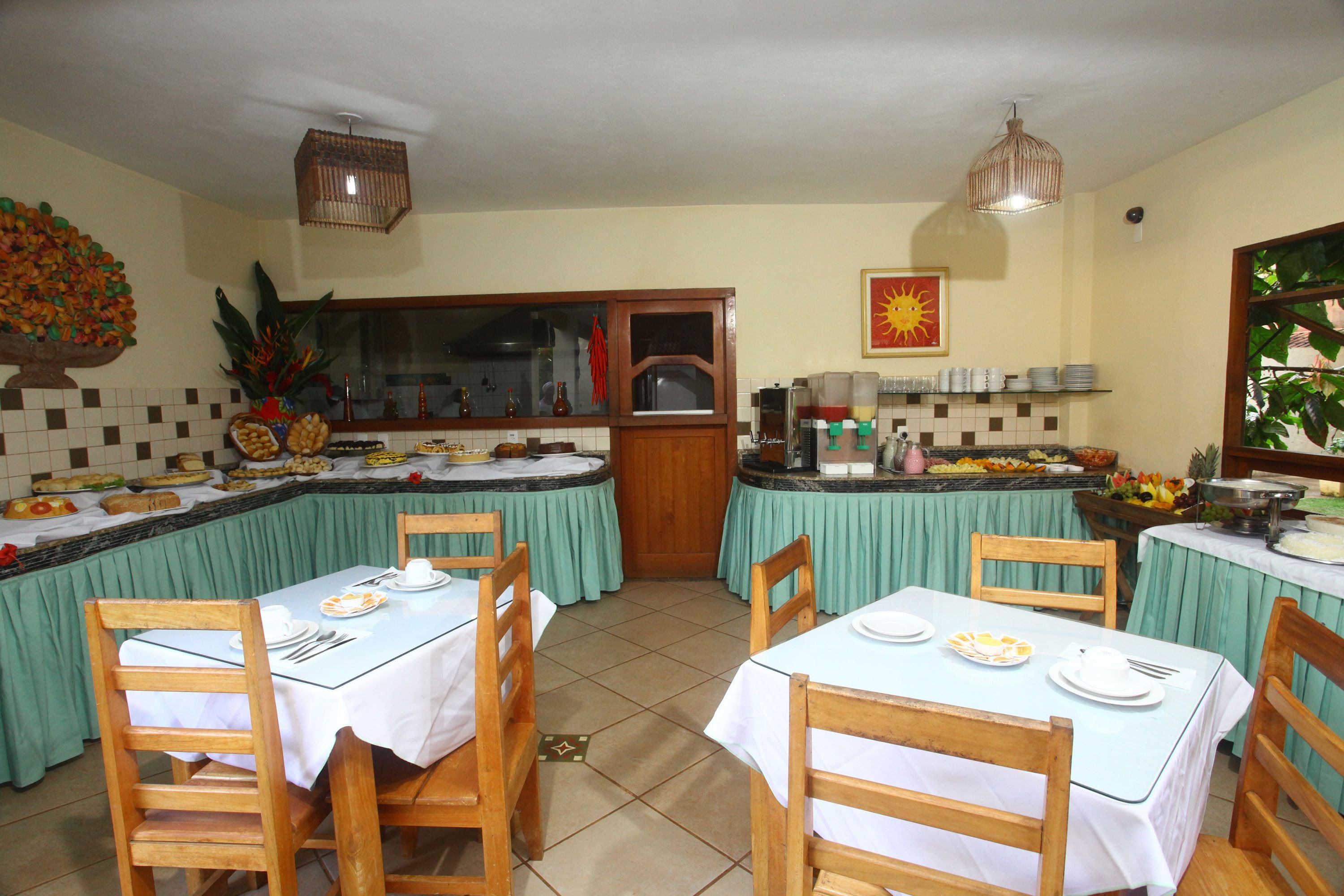 Un comedor con mesas y sillas, un espacio de cocina con barra libre, y un ventanal con vistas.