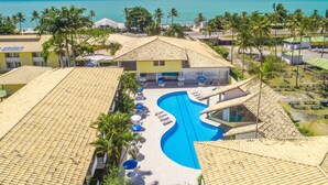 Un resort con piscina, palmeras y vistas al océano.