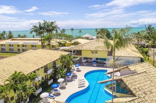 Un resort con piscina, tumbonas y vista al océano.