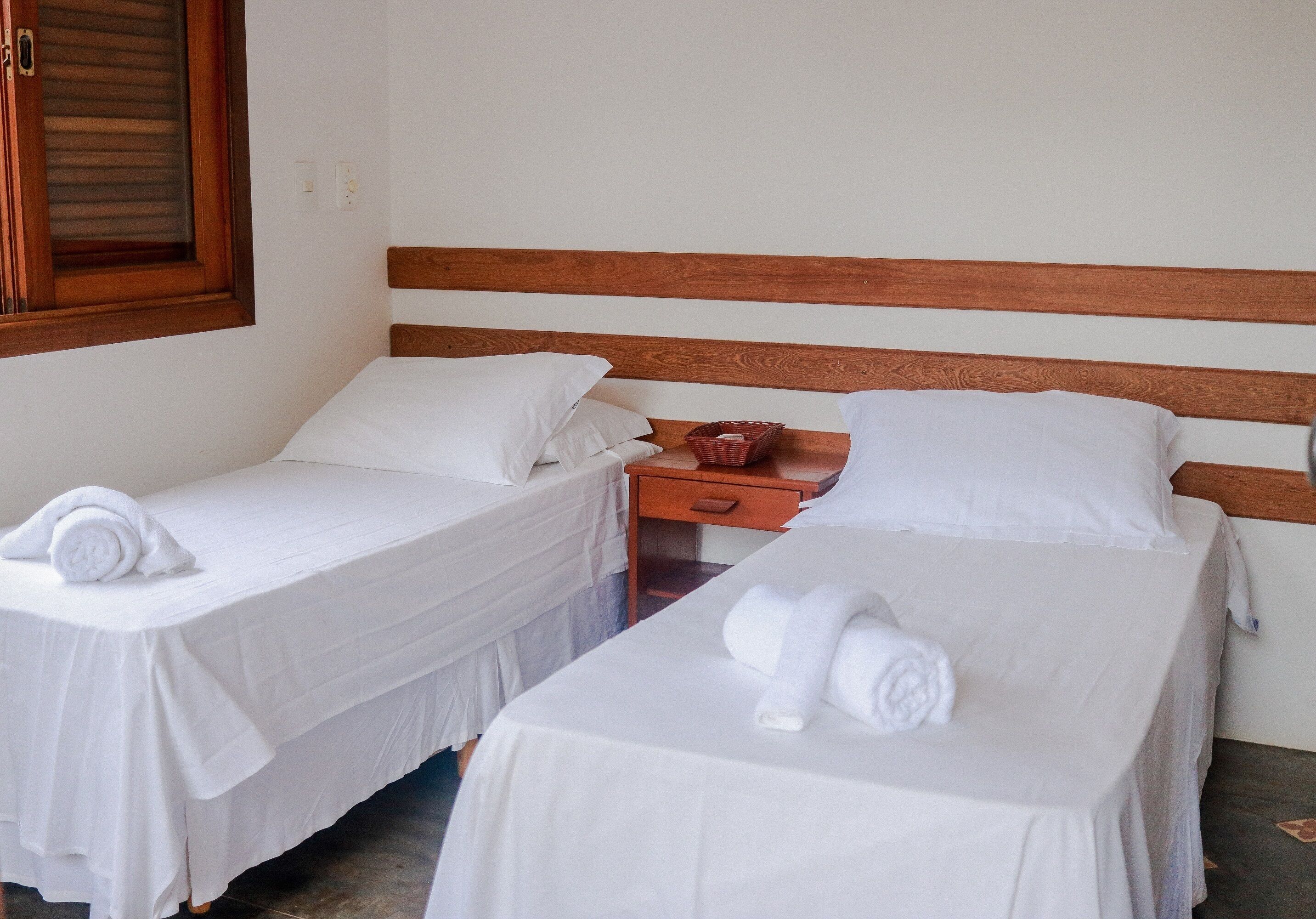 Two single beds with wooden headboards, white bedding, and neatly folded towels.