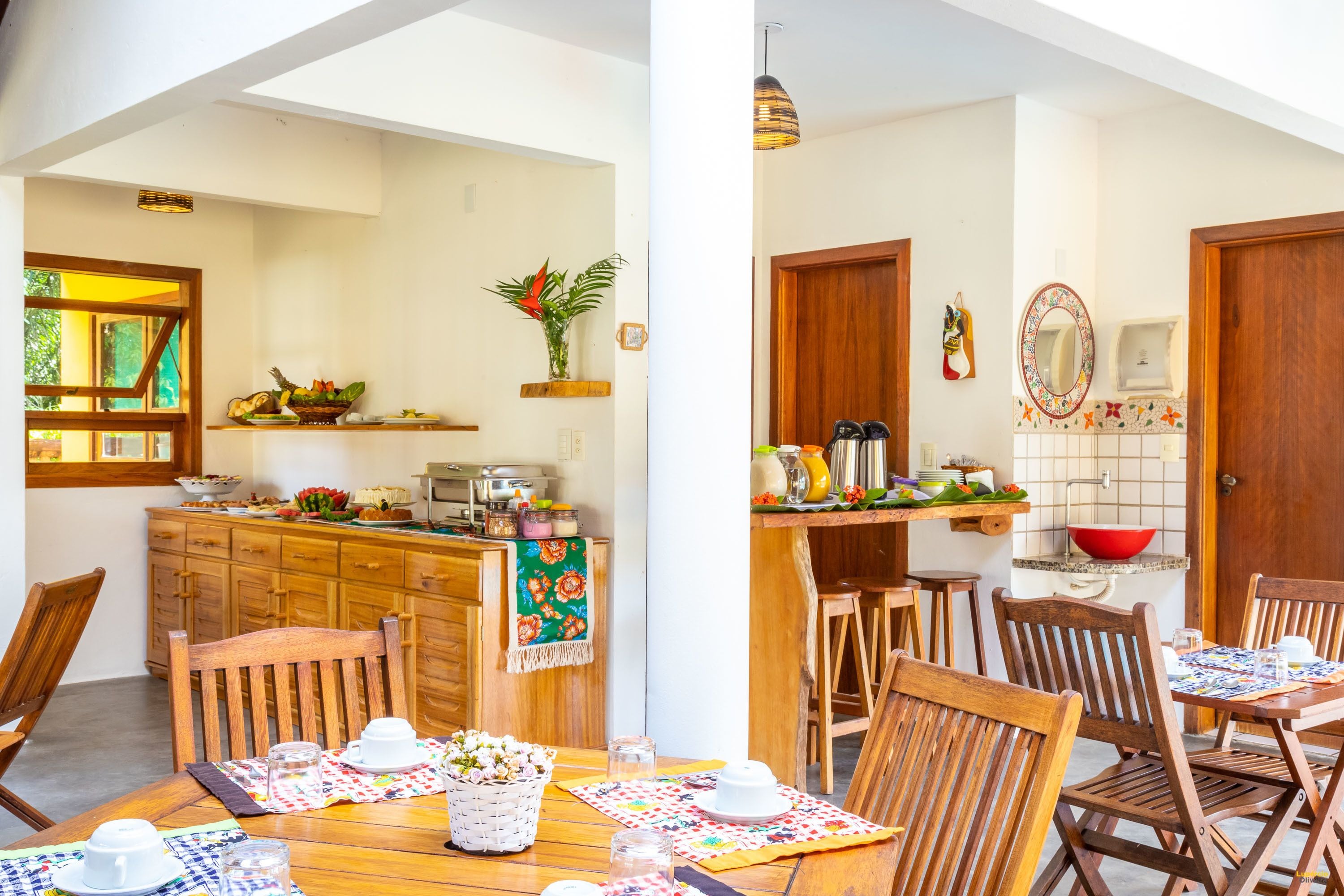 Un comedor con mobiliario de madera, una cocina con mostrador de madera y un baño con puerta de madera.