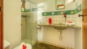 Un baño con ducha, inodoro, lavamanos y espejo.