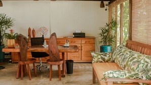 Una habitación acogedora con un escritorio de madera, dos sillas, un sofá y plantas en macetas.