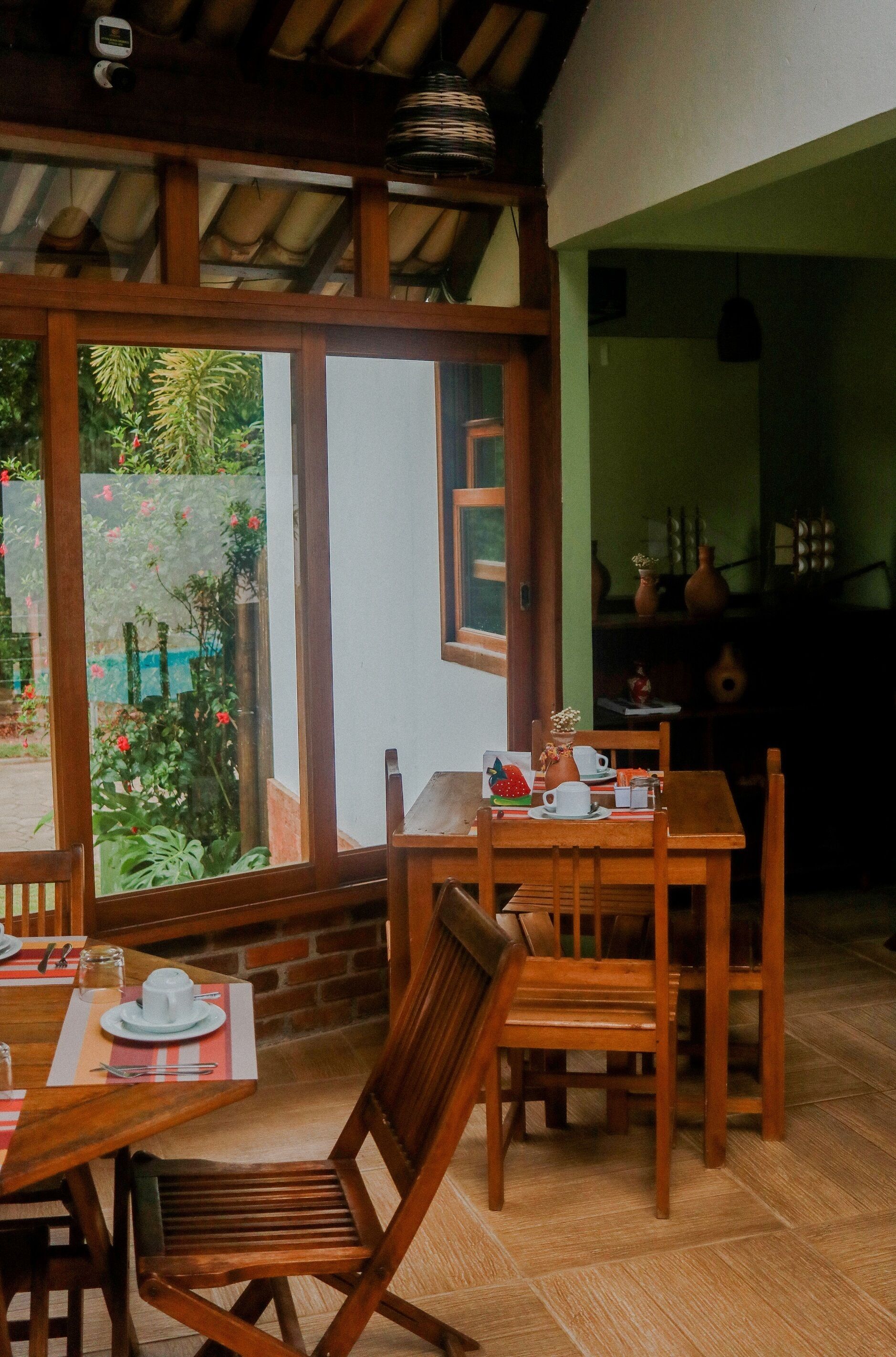 A dining area with wooden furniture and a view of a garden through a glass door.