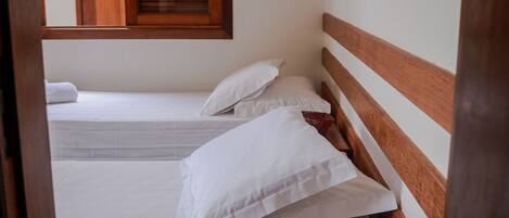 Un dormitorio con dos camas, cabeceros de madera y una ventana con persianas.