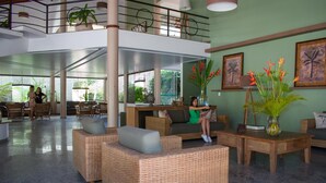 A spacious lobby with wicker furniture, a coffee table, and a vase with flowers. - Sarana Praia Hotel (Porto Seguro)