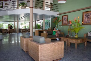 Un'ampia hall con mobili in vimini, un tavolino da caffè e un vaso con fiori.