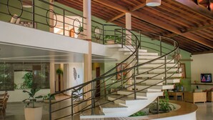 A spacious interior with a central spiral staircase, large potted plants, and a modern design. - Sarana Praia Hotel (Porto Seguro)