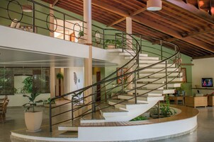 Un interno spazioso caratterizzato da una scala a chiocciola centrale, grandi piante in vaso e un design moderno.