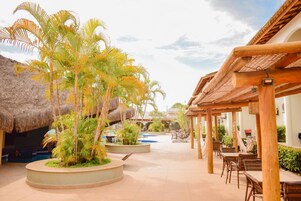 Un resort con piscina, palmeras y mobiliario para exteriores.