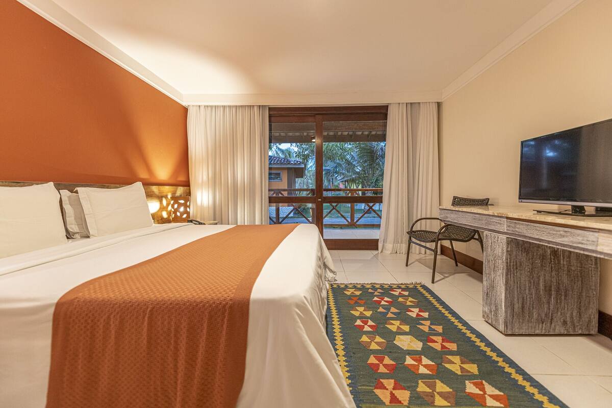 Une chambre d’hôtel avec un lit, un bureau avec une télévision et une vue sur l’extérieur.