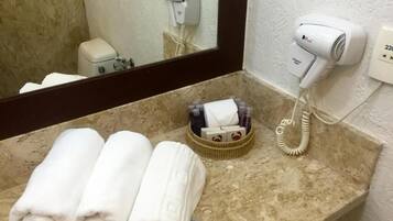 Un baño con encimera de mármol, un secador de pelo y un perchero con toallas.