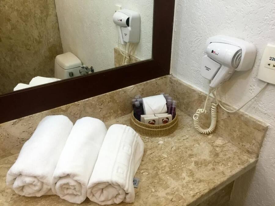 Un baño con encimera de mármol, un secador de pelo y un perchero con toallas.