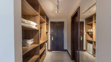 A narrow hallway with wooden shelving units on both sides, a door at the end, and a ceiling light fixture.