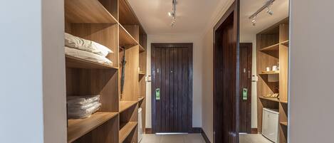 A narrow hallway with wooden shelving units on both sides, a door at the end, and a ceiling light fixture.