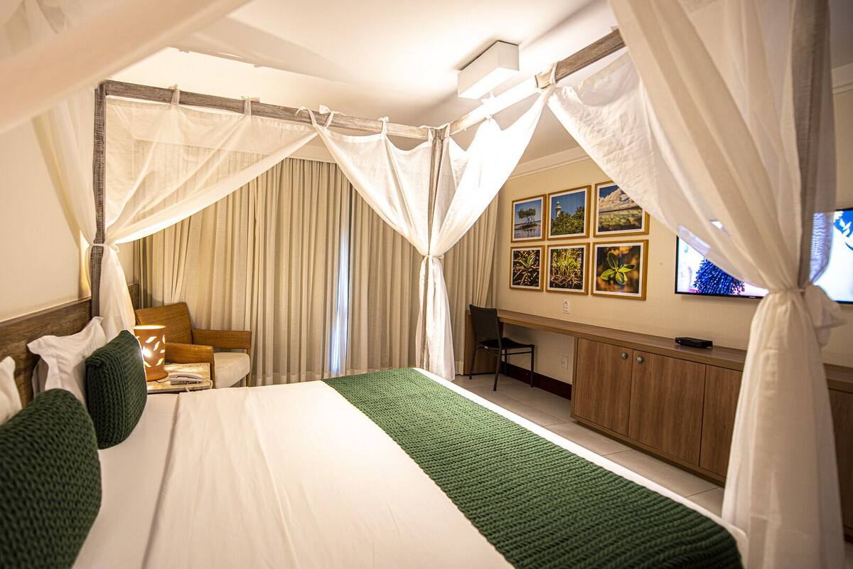 Une chambre d’hôtel avec un lit, un bureau, une chaise et un téléviseur.