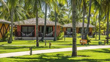 Un resort con varias edificaciones tipo bungalow, cada una con techo de tejas y un balcón. Cuenta con un césped cuidado y un camino que conduce a las construcciones.