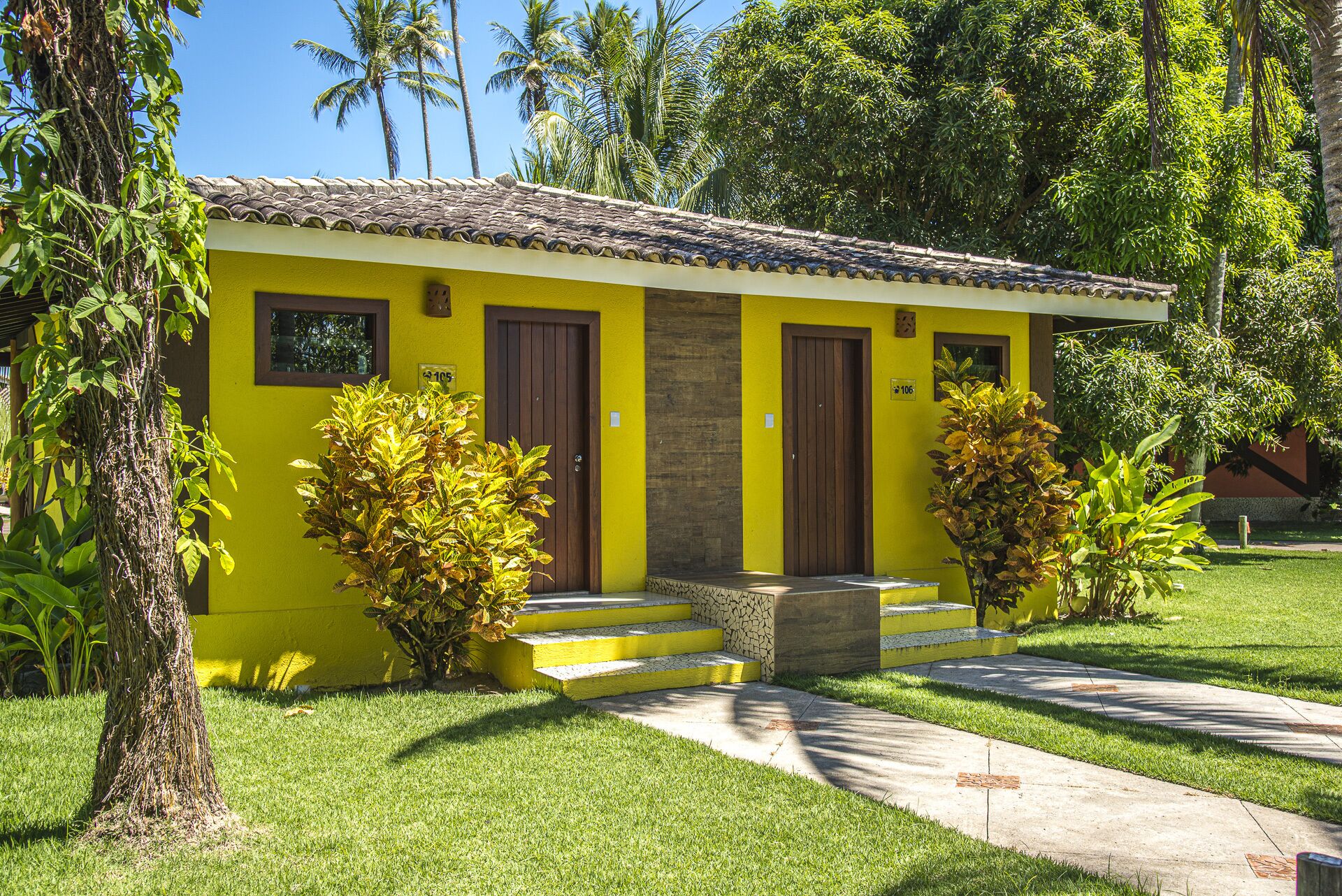 A yellow building with two wooden doors, a small porch, and steps leading to the entrance.