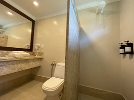Un baño con inodoro, dispensador de toallas, secador de pelo y dispensador de jabón.