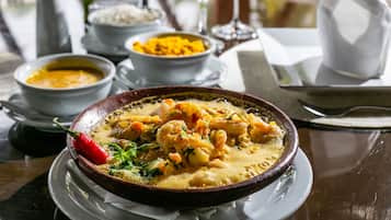 Uma mesa com um prato de curry, um pimentão vermelho e um copo de água.