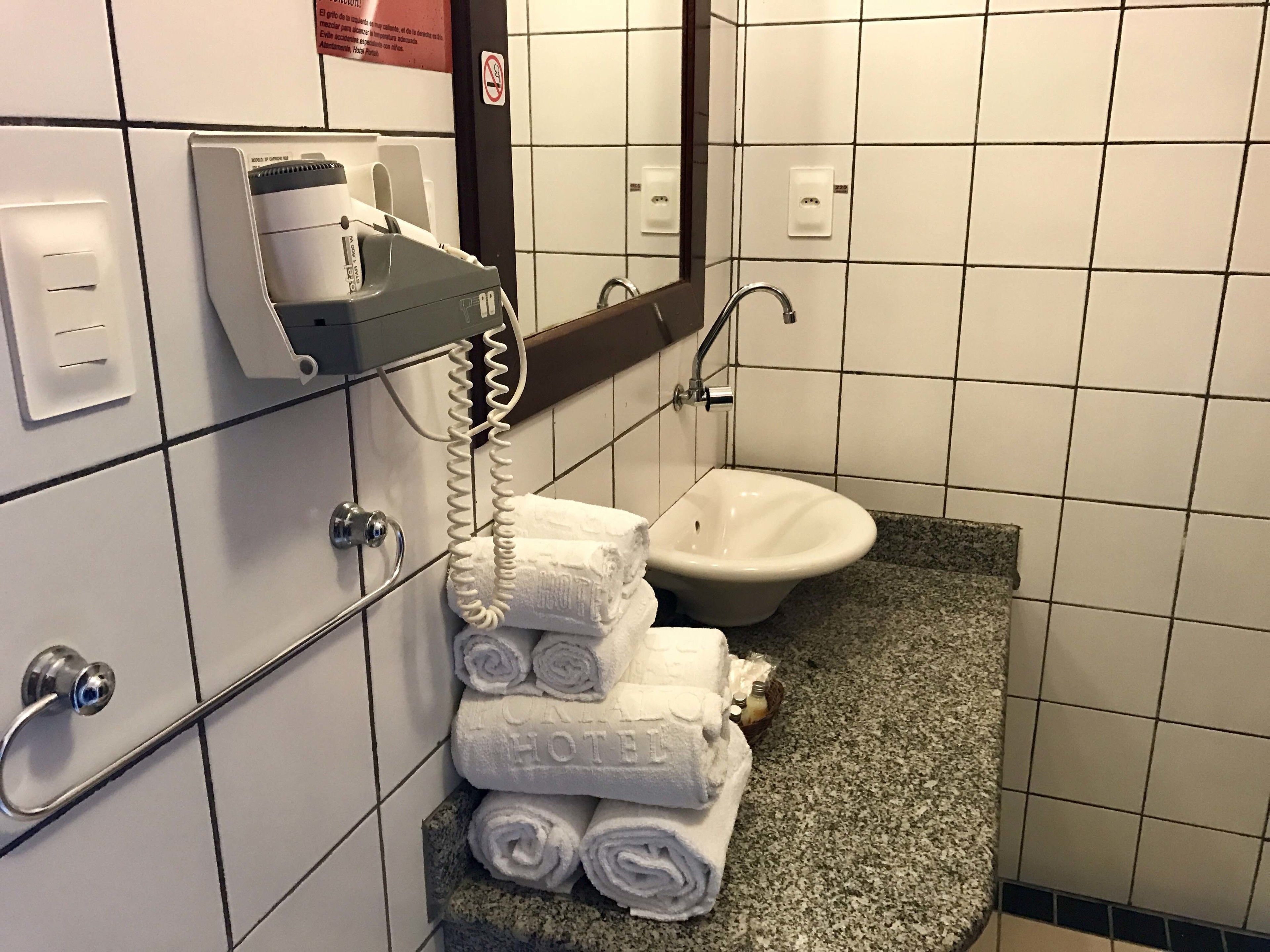 A hotel bathroom with a sink, a towel dispenser, and a telephone.