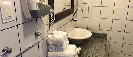 A hotel bathroom with a sink, a towel dispenser, and a telephone.