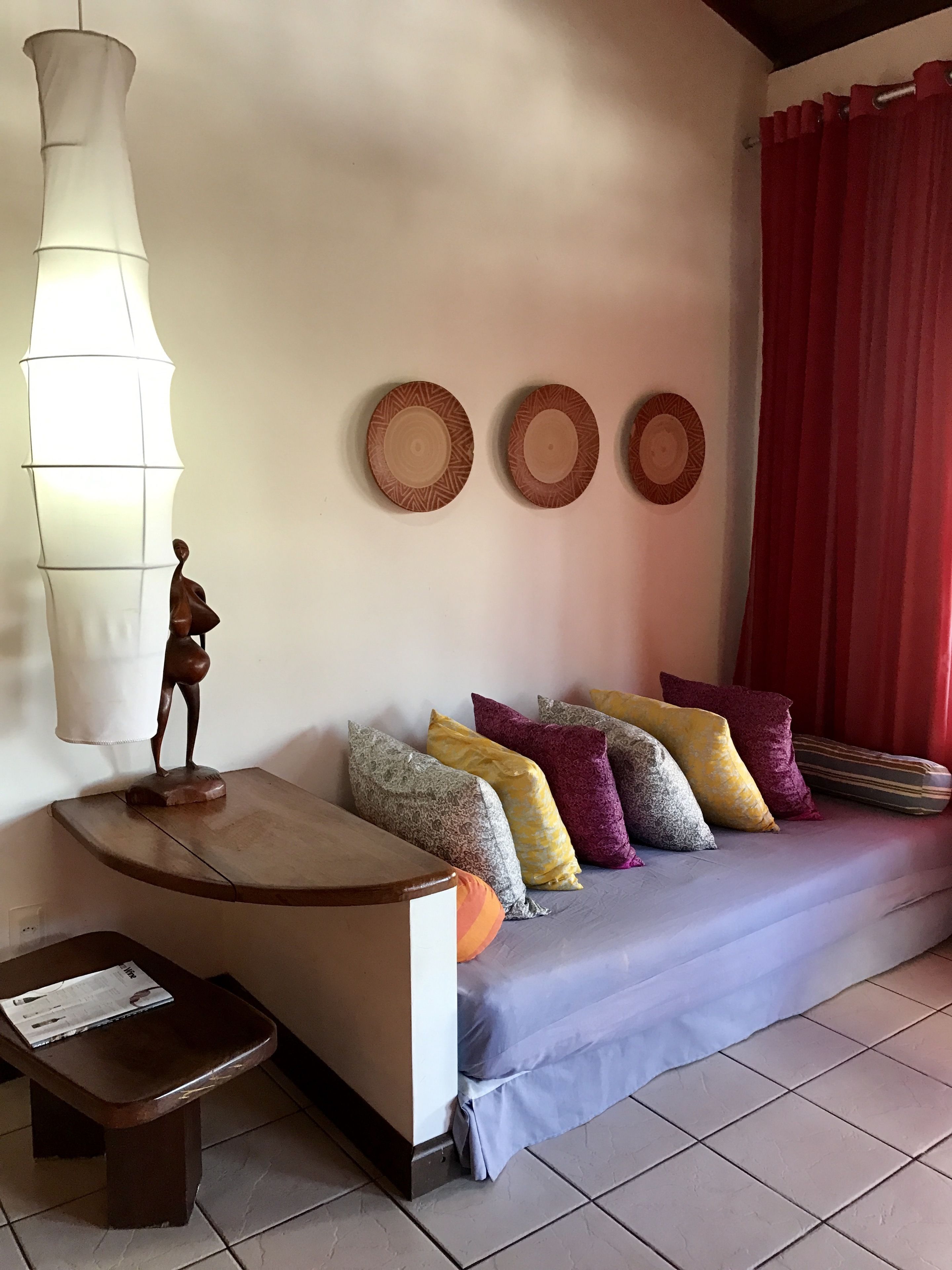 Un salon avec un canapé, des coussins, une table et une lampe fixée au mur.