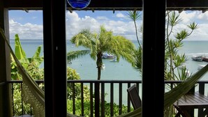 A balcony with a view of the sea, a hammock, and a table. - Hotel Portaló (Cairu)